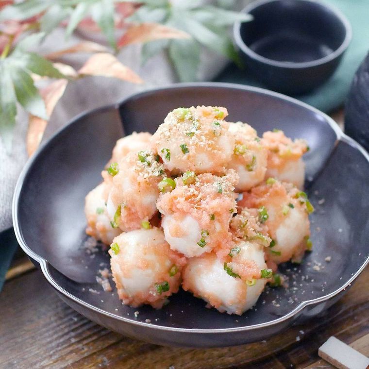 黒灰色の皿に盛りつけられている里芋と小口ねぎの明太子バター和え