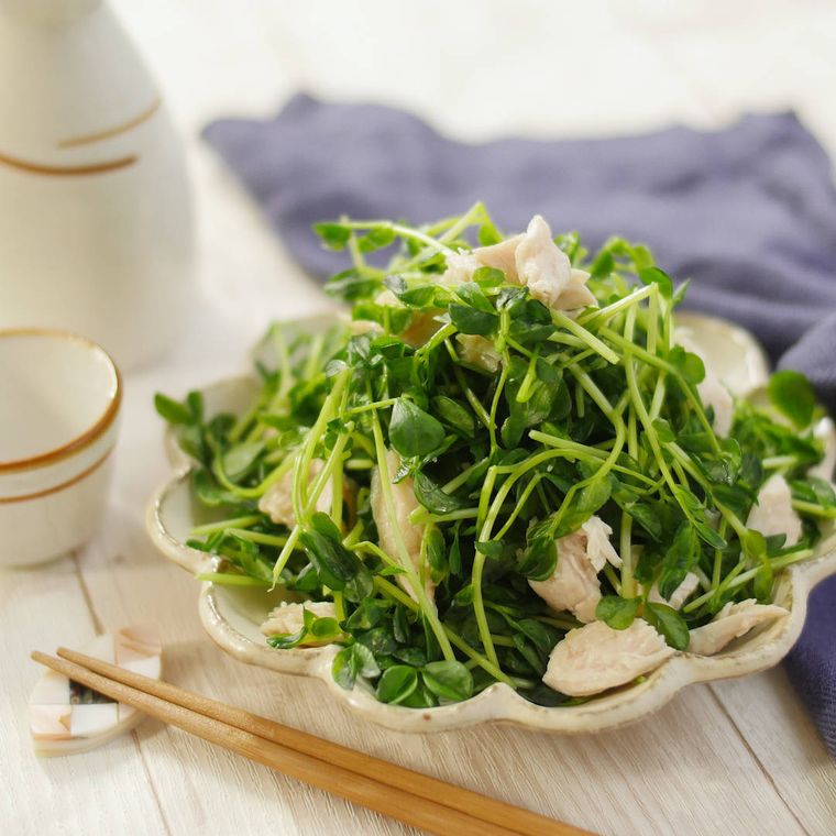 白い花形の皿に盛りつけられた豆苗のやみつき塩レモンささみサラダ