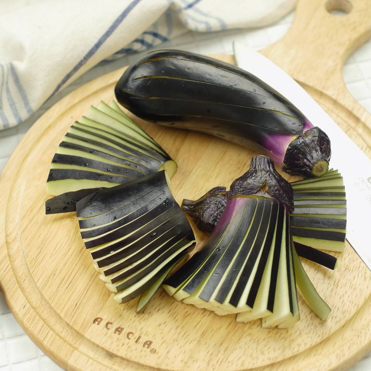 カッティングボードに置かれた丸ごとなすと飾り切りされたなす