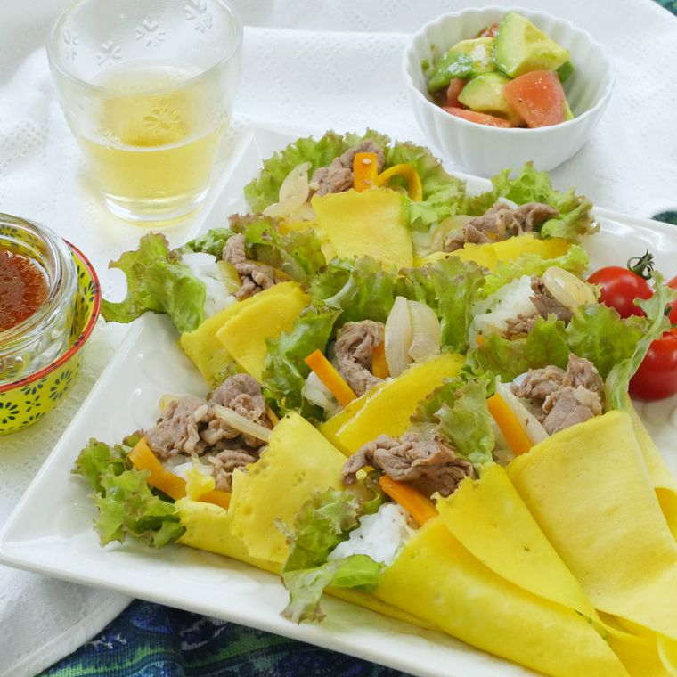 白い角皿に盛りつけられた、牛肉とサニーレタス入り薄焼き卵巻き