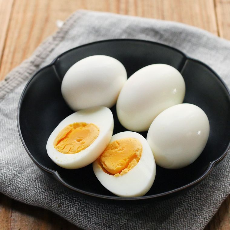 花びら形の黒い小鉢に盛りつけられた丸ごとと半分カットのゆで卵