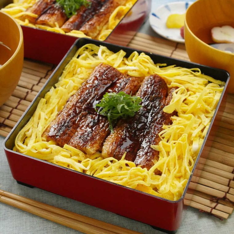 赤い重箱に盛りつけられたちくわの蒲焼きと錦糸卵入りのお重