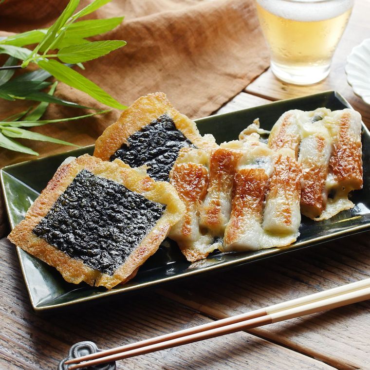 濃色の長皿に盛りつけられたパリパリ羽つきの磯辺焼き風ちくわに、箸置きに置かれた箸とビール入りのグラスが添えられている