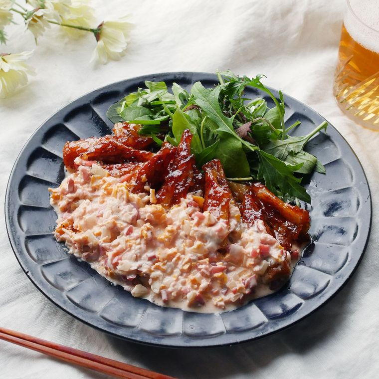 花びら模様のグレー色皿に盛りつけられた梅タルタルのちくわ南蛮に、箸とビール入りのグラスが添えられている