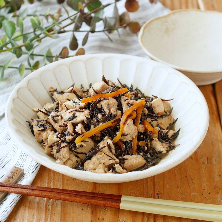 白い皿に盛りつけられた豆腐とひじき、にんじん入りの甘辛炒め煮