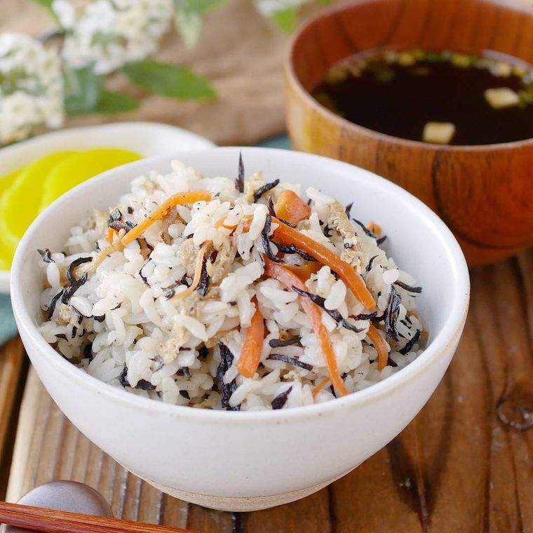 白い茶碗に盛りつけられたひじきと油揚げ、にんじんの混ぜごはん