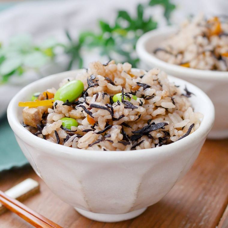 白い茶碗に盛りつけられたひじきと枝豆、油揚げの炊き込みごはん