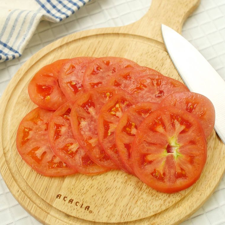 丸いカッティングボードの上で輪切りにされたトマト