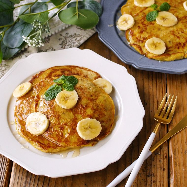 縁取りのある皿に盛りつけられたバナナのパンケーキ