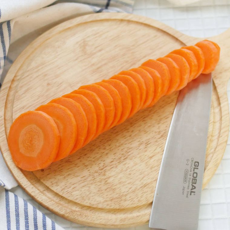 丸いカッティングボードの上で輪切りにされたにんじん