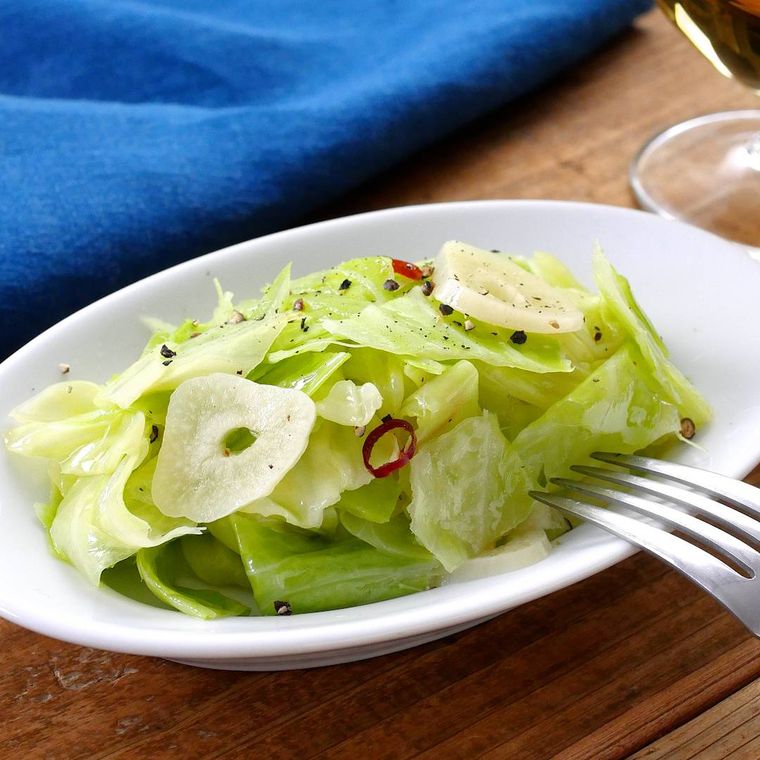 白い皿に盛りつけられたキャベツとにんにくのペペロンチーノ風