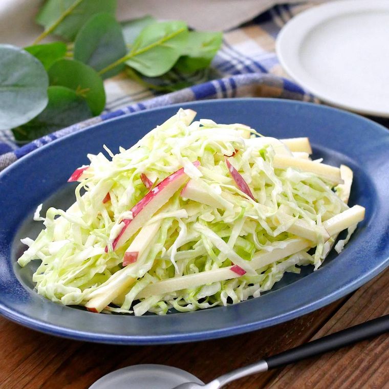 青い皿に盛りつけられているキャベツとりんごのマヨネーズサラダ