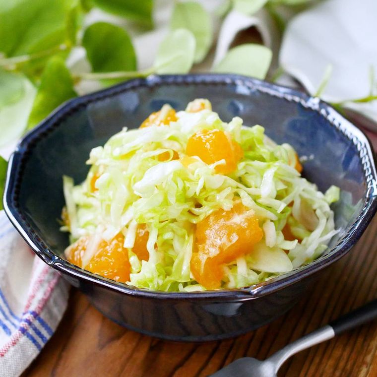 藍色の小鉢に盛りつけられているキャベツとみかん入りのサラダ