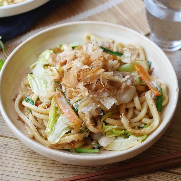 白い皿に盛りつけられた豚バラ肉と野菜入りの焼きうどん
