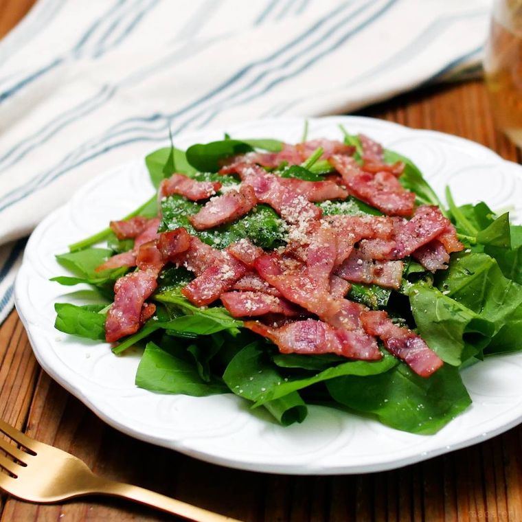 白色の丸皿に盛られたサラダほうれん草とベーコンのサラダ