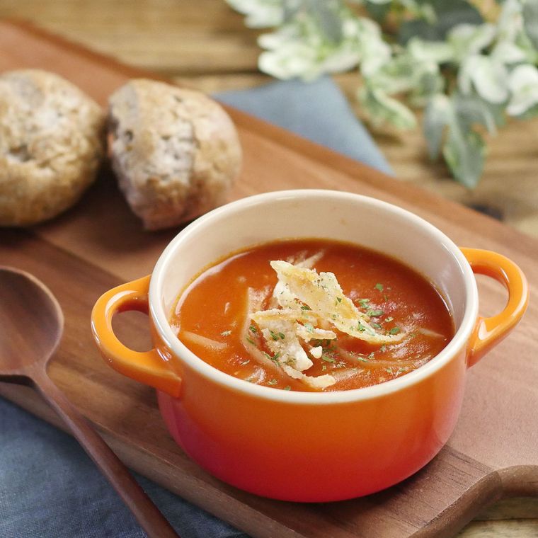 オレンジ色の器に盛った揚げじゃがいも入りトマトスープ