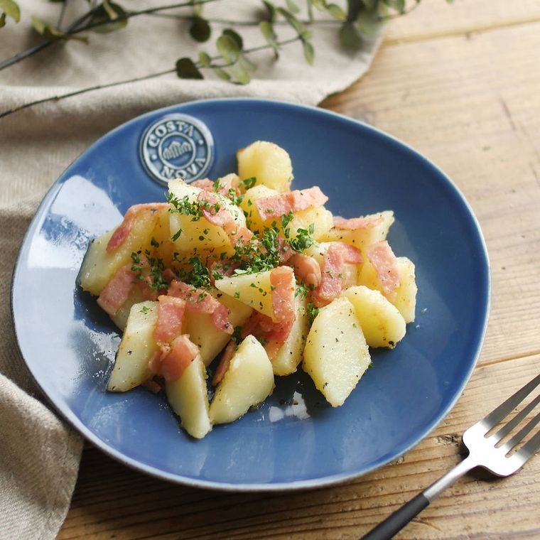 青い皿に盛られたじゃがいもとベーコンのバター炒め