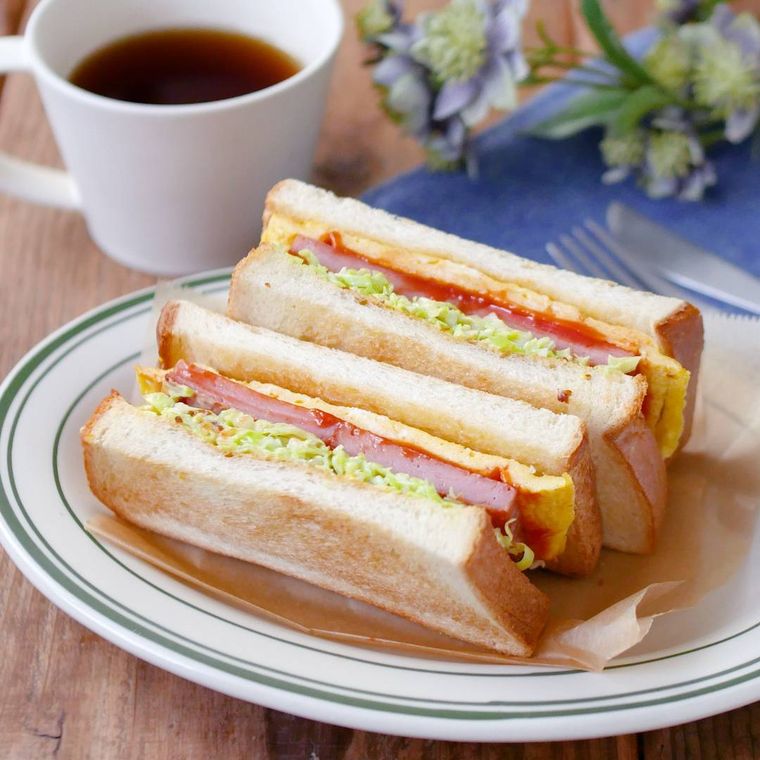 緑の縁が入った白のお皿に盛られたスパムサンドイッチ