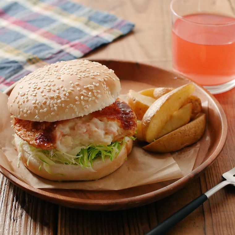 木の皿に盛りつけたグラタンコロッケハンバーガーとフライドポテト