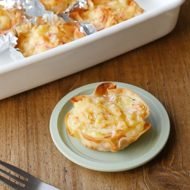 白い保存容器に入っているカニかまグラタンを小皿に取り分けた様子