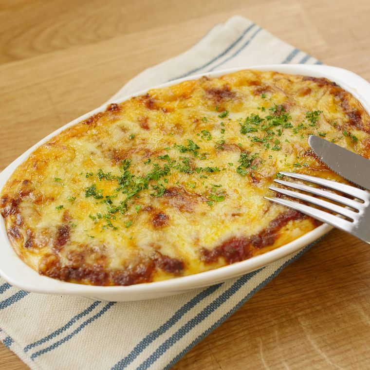 白いグラタン皿に入っている餃子の皮と2種類ソースのラザニア風