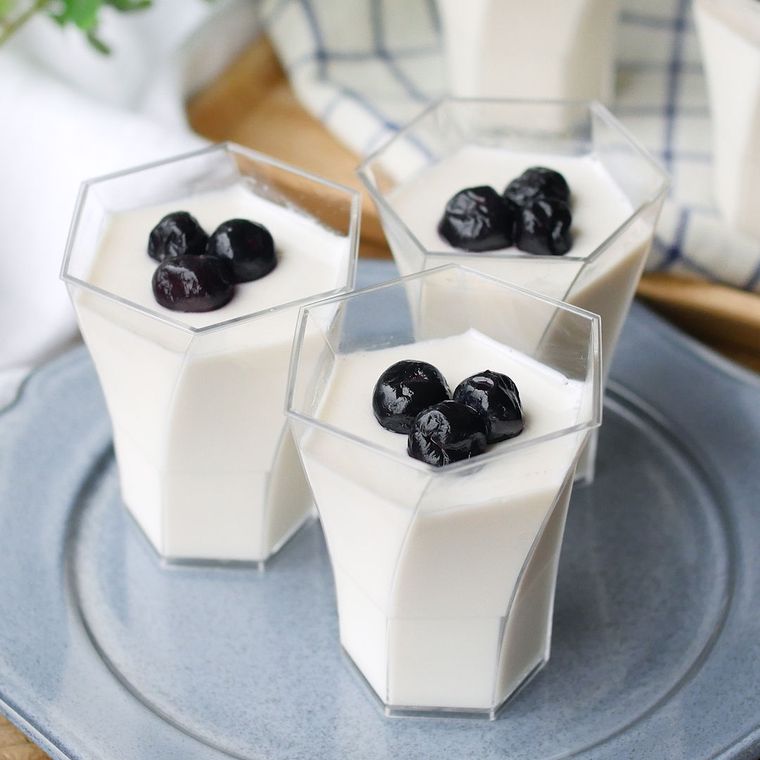 グレーの皿に並べた、透明なカップに入ったブランマンジェ