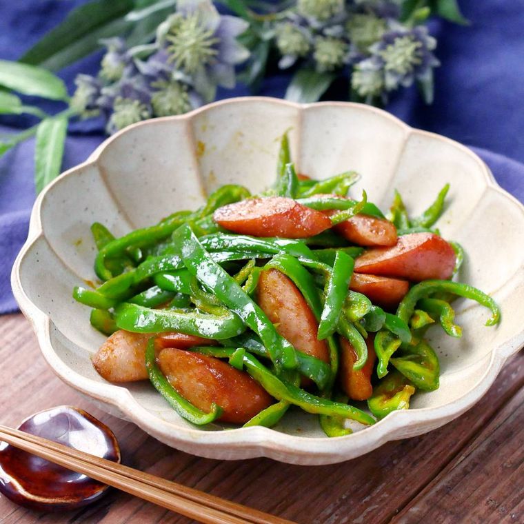 白い花型の皿に盛り付けたピーマンとウインナー炒め