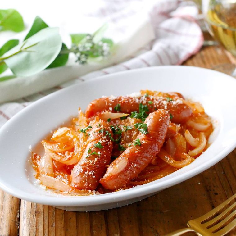 白い楕円形の皿に盛り付けたウインナーと玉ねぎのナポリタン炒め