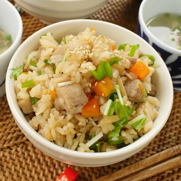 白い茶碗に盛りつけられた、豚バラ肉とにんじんの炊き込みごはん
