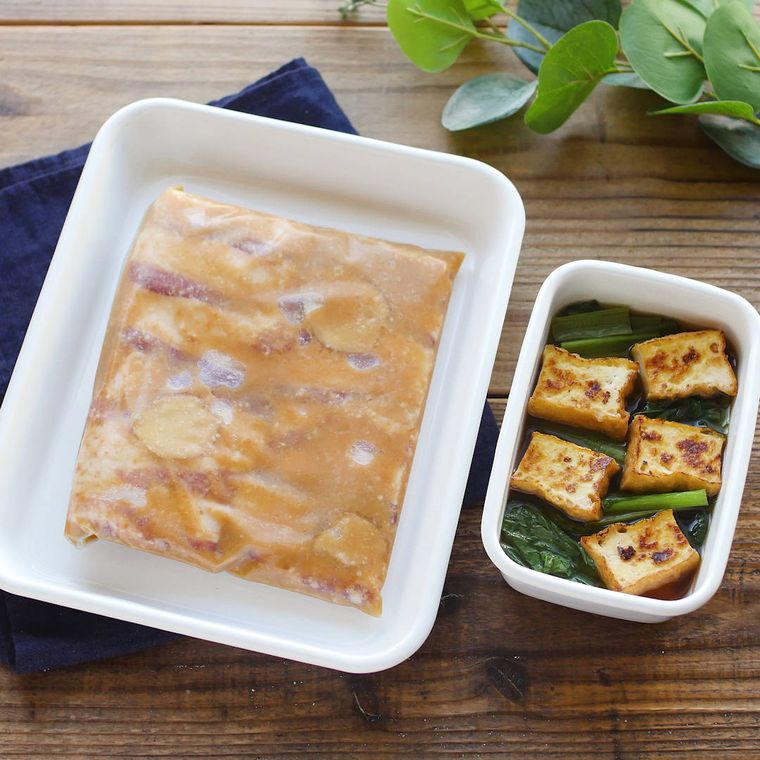白い保存容器に入っている厚揚げと小松菜の煮物