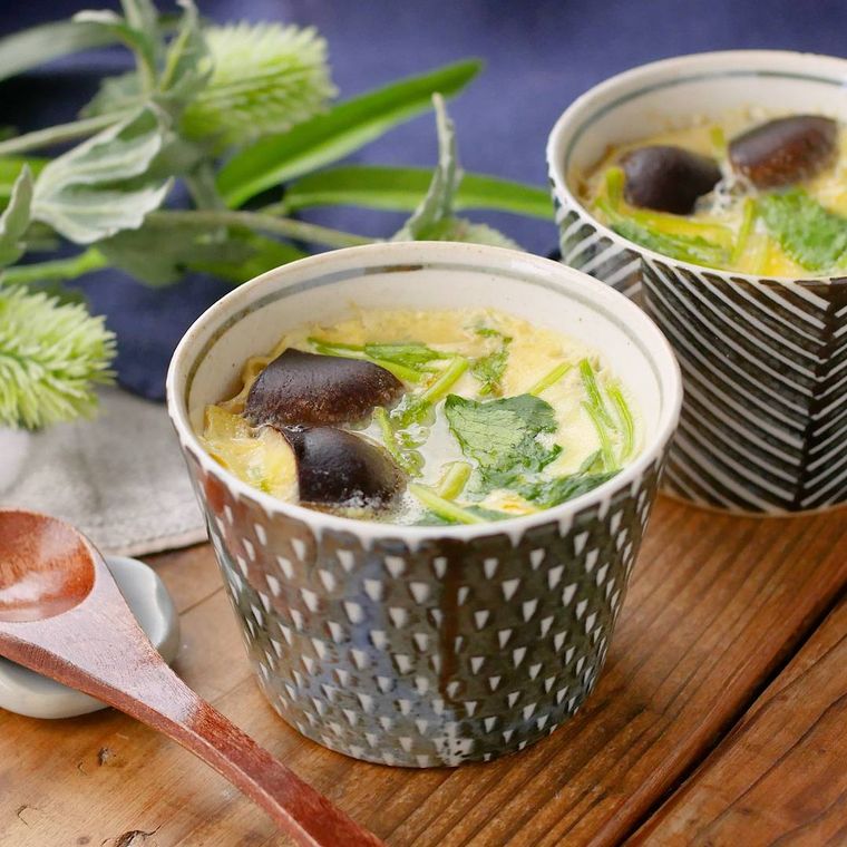 幾何学模様の器に入っているしいたけと三つ葉、かまぼこの茶碗蒸し