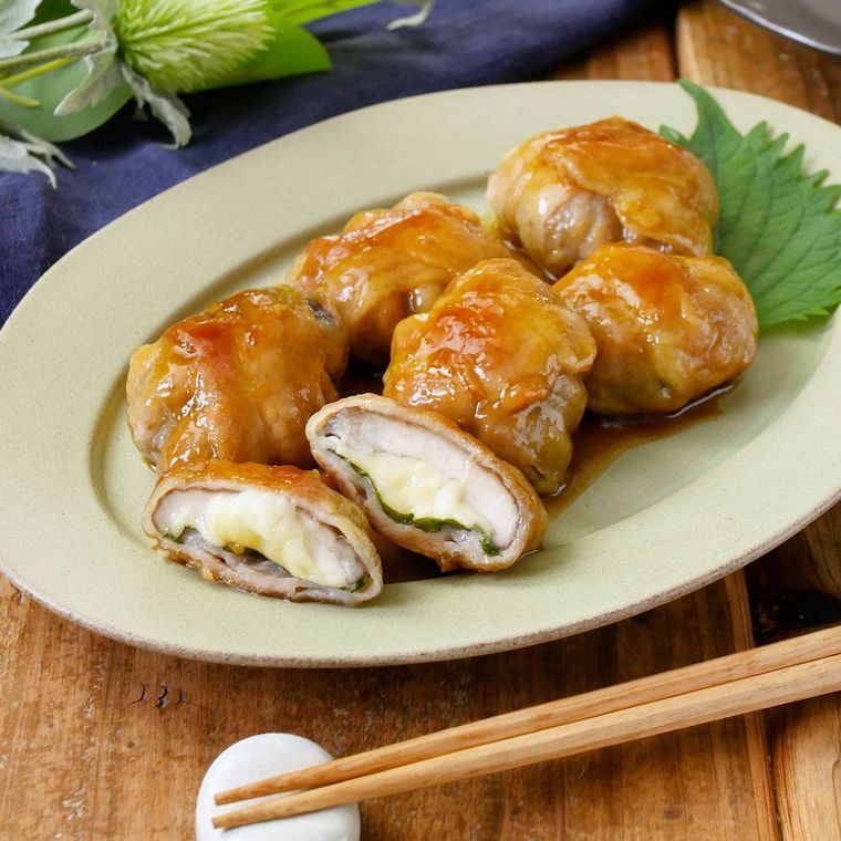 淡色の皿に盛りつけられたチーズと大葉、しいたけの豚バラ肉巻き