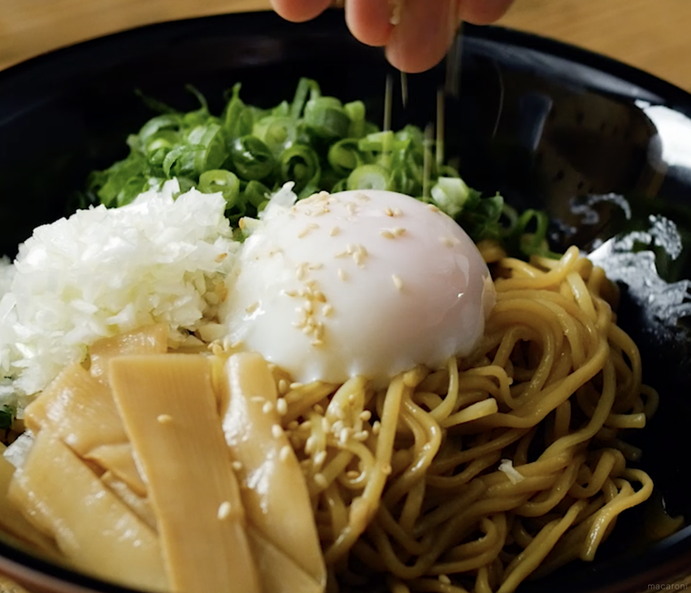 黒い丼に油そばを盛り付ける様子