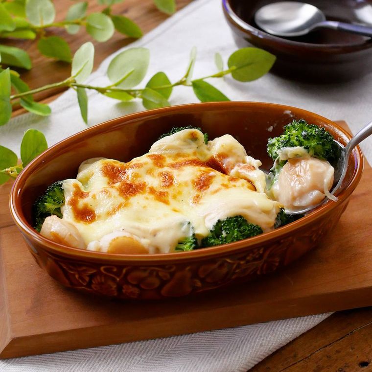 赤茶色の耐熱容器に入っている帆立貝柱とブロッコリーのグラタン