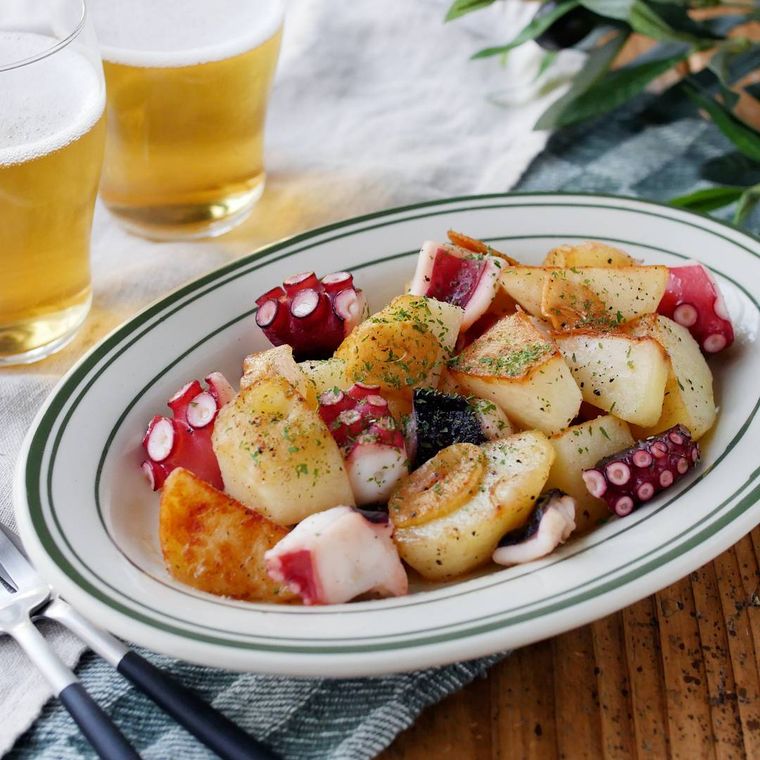 緑色の縁取りがある皿に盛りつけられているたこのガーリック炒め