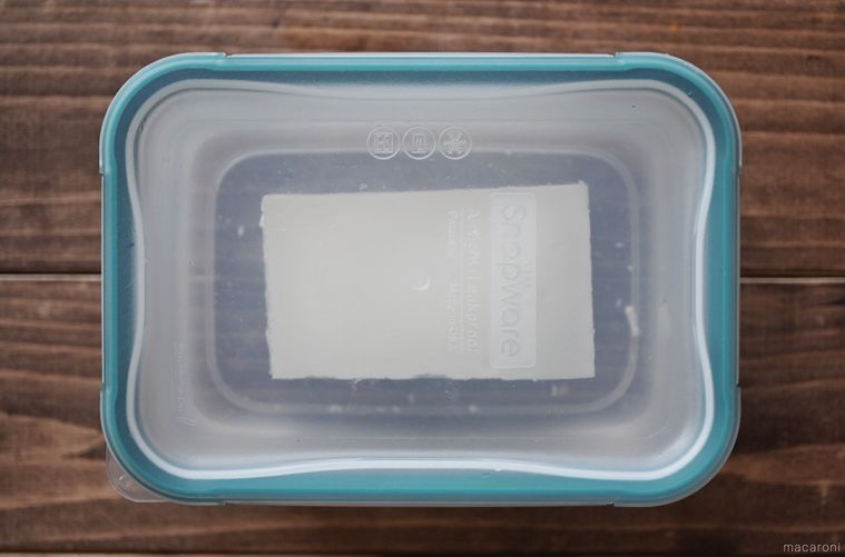 水と豆腐が入った、蓋がされた保存容器