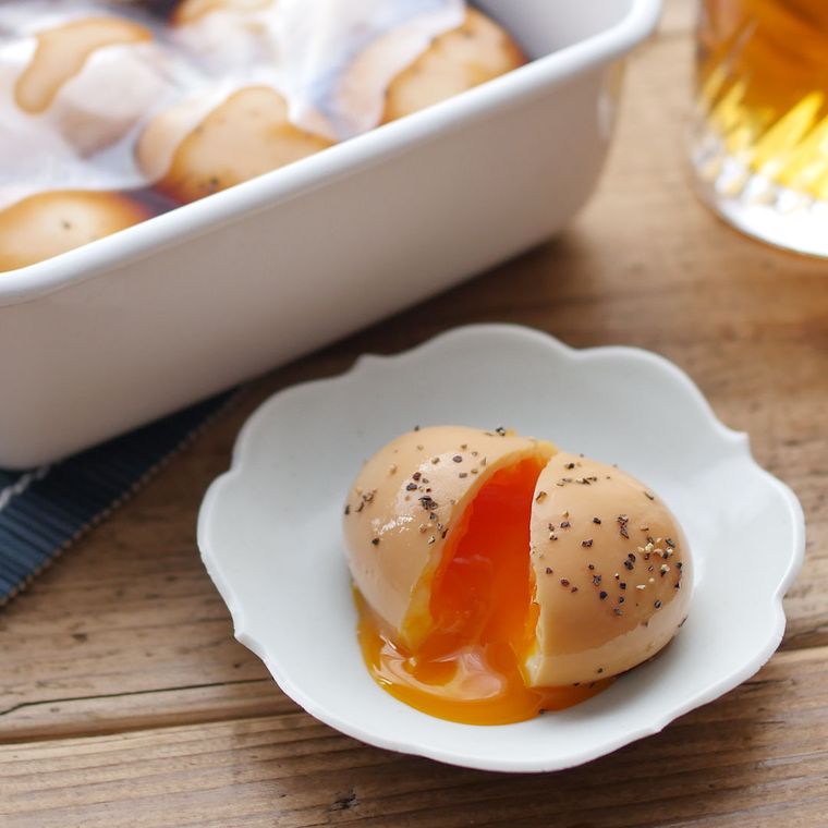 白い容器に入っている味付きゆで卵を小皿に取り分け割った様子