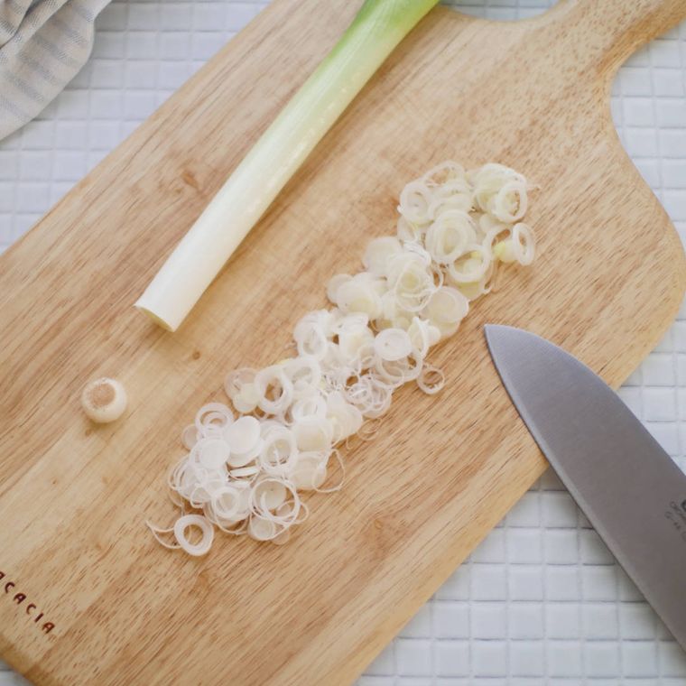 まな板の上に置かれた長ねぎを小口切りしている様子