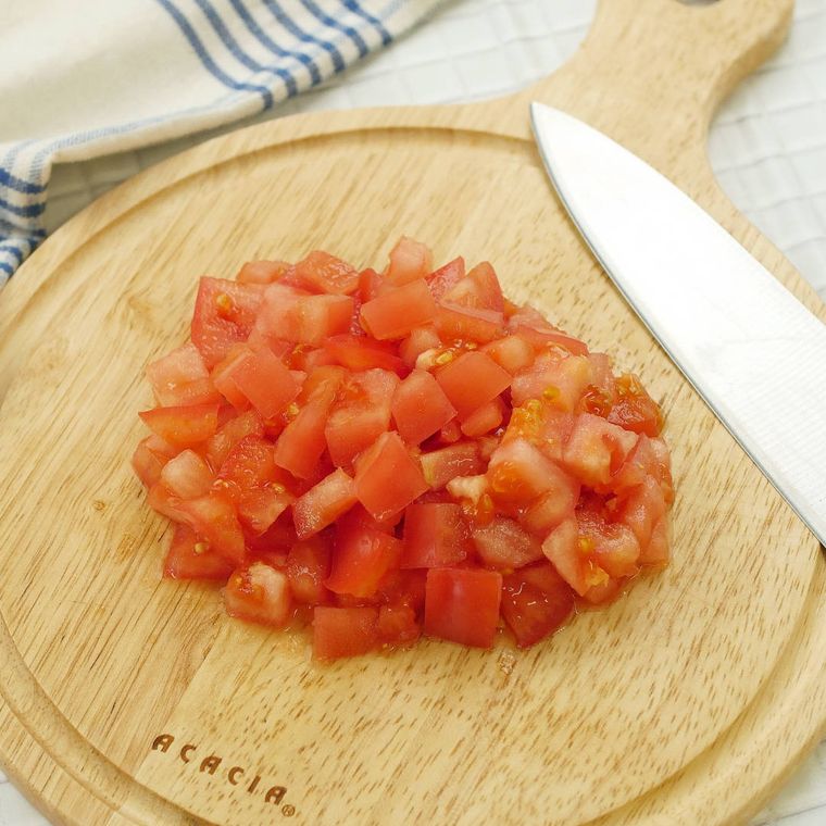 丸いカッティングボードの上で角切りにされたトマト