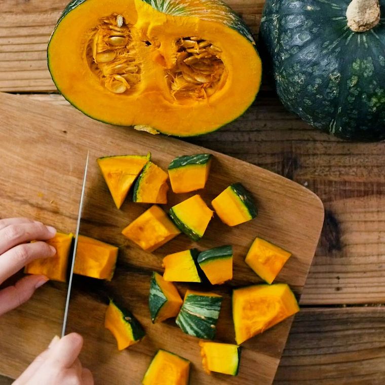 半分に割ったかぼちゃをまな板の上で均等に角切りしている様子