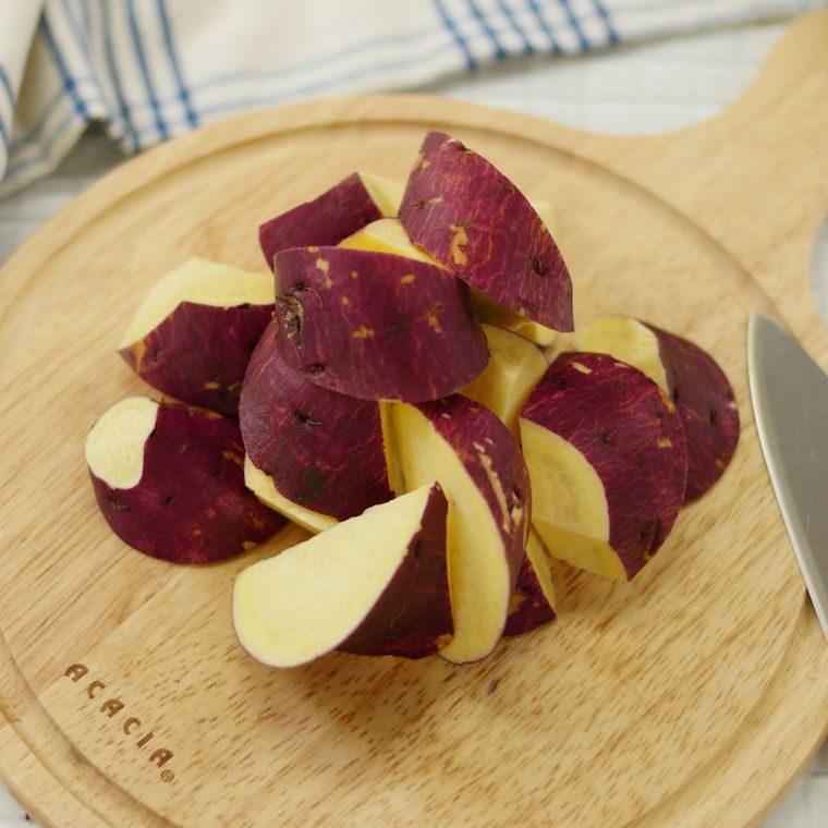 丸いカッティングボードの上で乱切りされているさつまいも