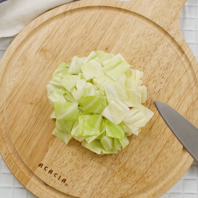 丸いカッティングボードの上で色紙切りにされたキャベツ