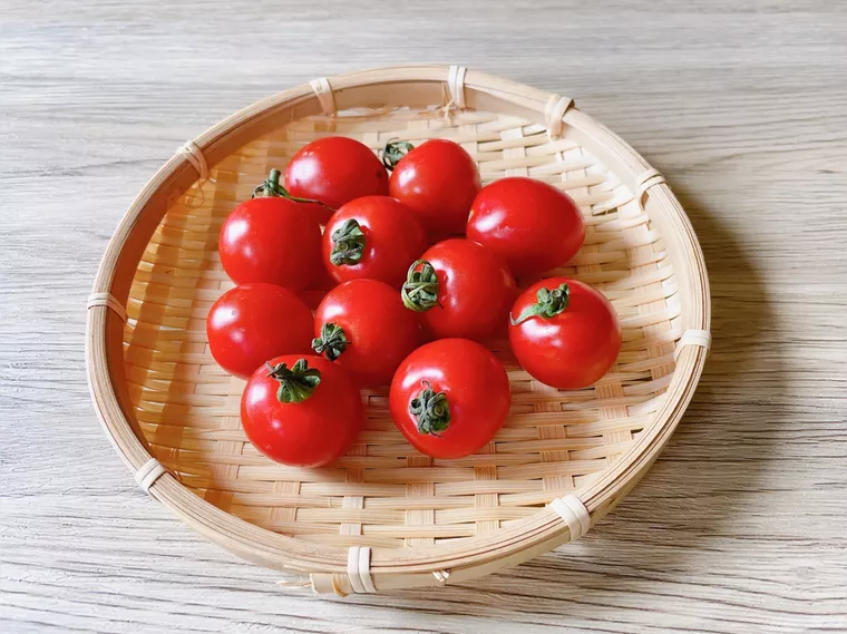 竹ざるに盛りつけられているたくさんのミニトマト