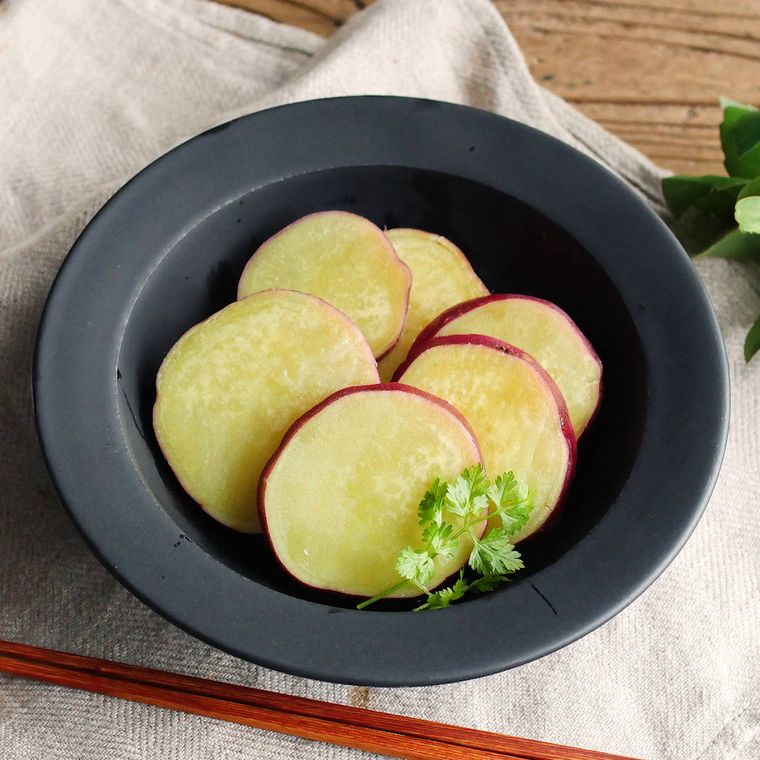 黒色の丸皿に盛られたさつまいものレモン煮