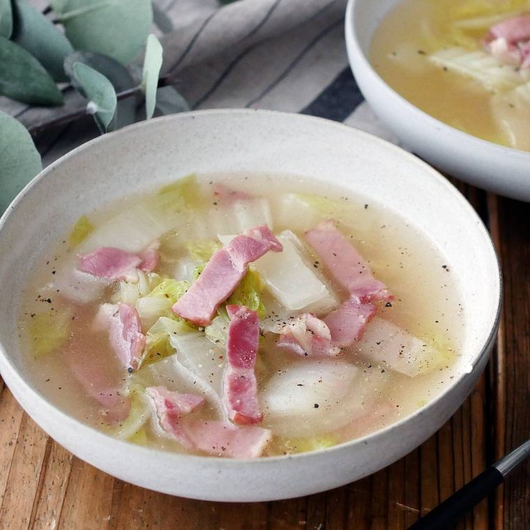 白いボウルに盛りつけられている白菜とベーコン入りのチキンスープ