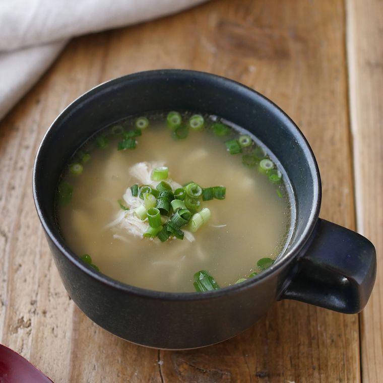 黒いカップに盛りつけられている鶏ささみとしょうが入りのスープ