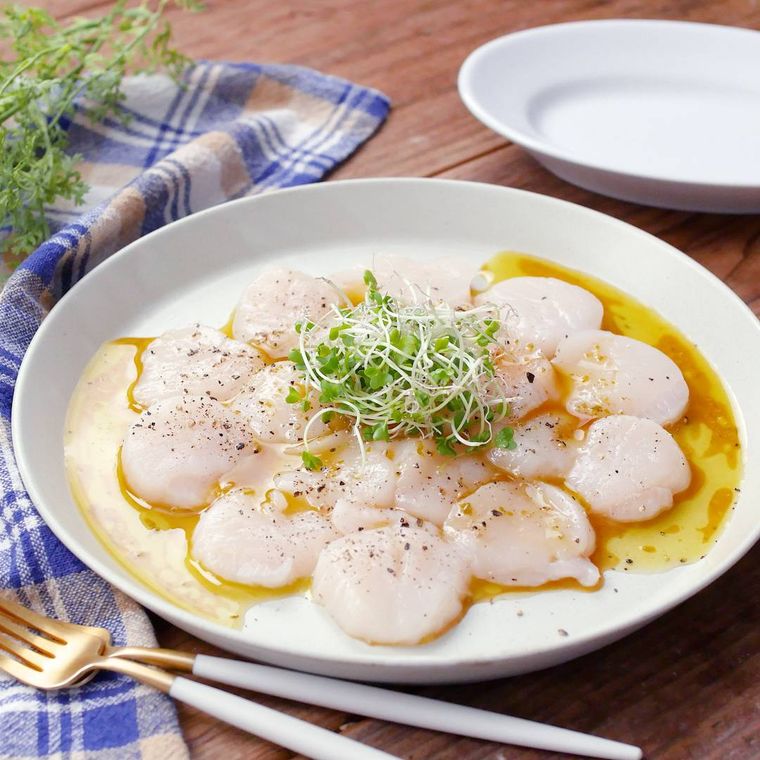 皿に盛りつけかいわれ大根をトッピングした帆立貝柱のカルパッチョ
