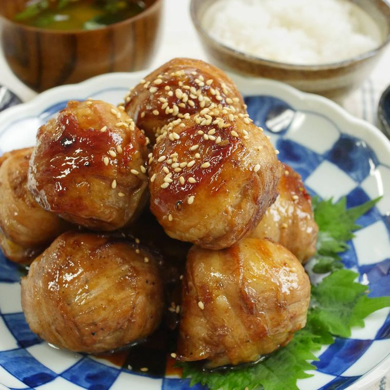 皿に盛りつけられたまるごと里芋の肉巻きにごはんとみそ汁が添えられている