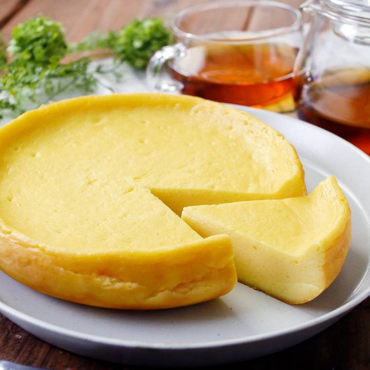 丸い皿に盛りつけられた炊飯器で作るさつまいもチーズケーキに紅茶が添えられている