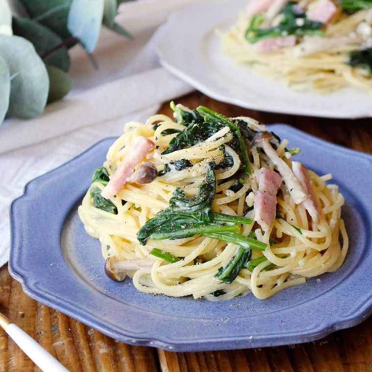 青い皿に盛られたほうれん草とベーコンのクリームパスタ